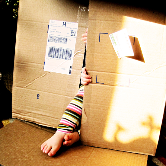 toddler hiding in cardboard shipping box